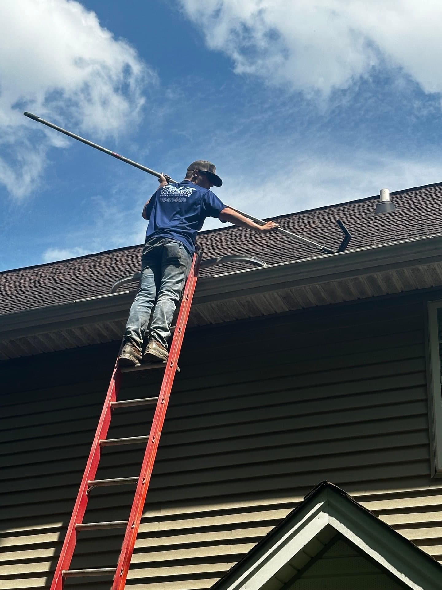 Technician on ladder performing professional roof cleaning in Nashville, TN